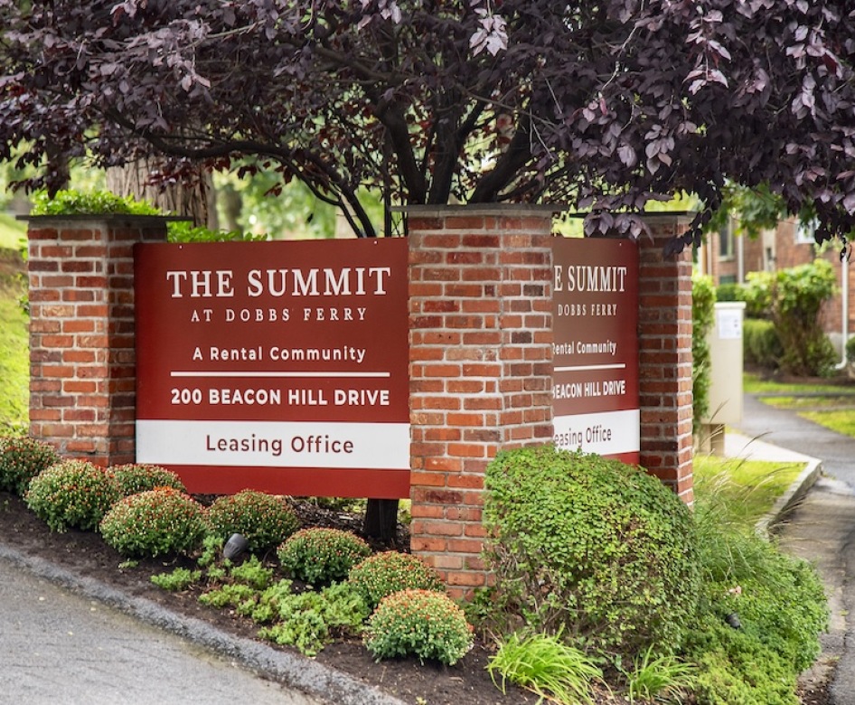 a large grassy area with trees and a brick building